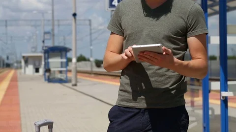 Young man looks happy while browsing internet on tablet on the train station Stock Footage 78655418