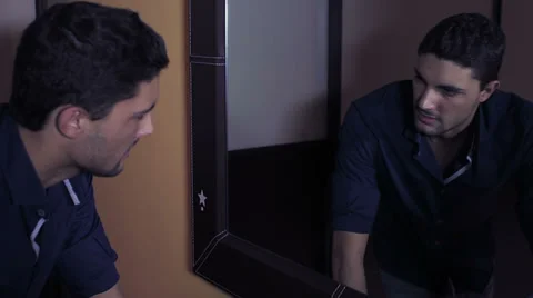 Young man looks at himself in reflection of mirror Stock Footage 34272013