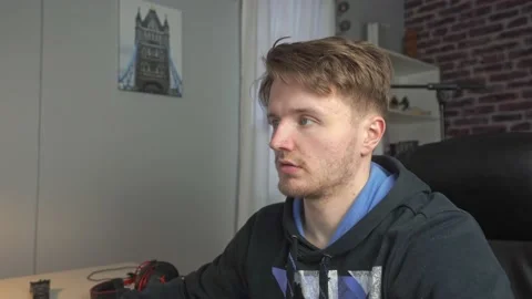 A young man looks at his computer screen then looks at the viewers and Stock Footage 205175367