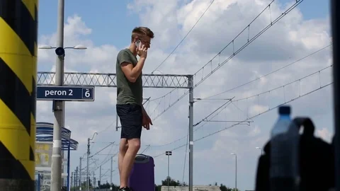 Young man looks irritated while speaking on cellphone on the platform Stock Footage 78652505