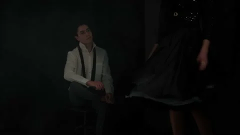 A young man looks passionately at a dancing girl in a dark room. 스톡 동영상 148501970