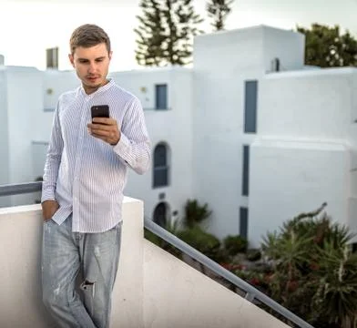 Young man looks at the a smartphone, summer outside, place for text, phone Stock Photos