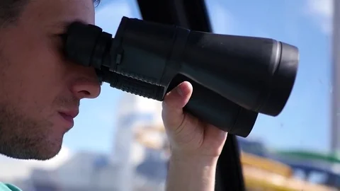 A young man looks through binoculars, watches and chews food. HD, 1920x1080 Stock Footage 78190452