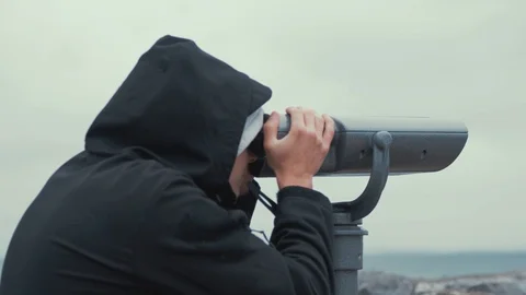 Young man looks through sightseeing binoculars bird watching spotting at Stock Footage 104669096