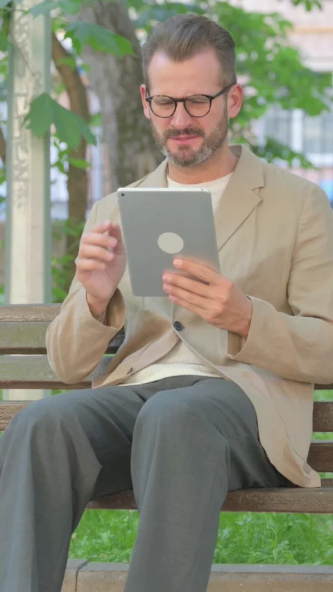 Young Man with Loss on Tablet while Sitting Outdoor, Vertical Video Video stock 319047712