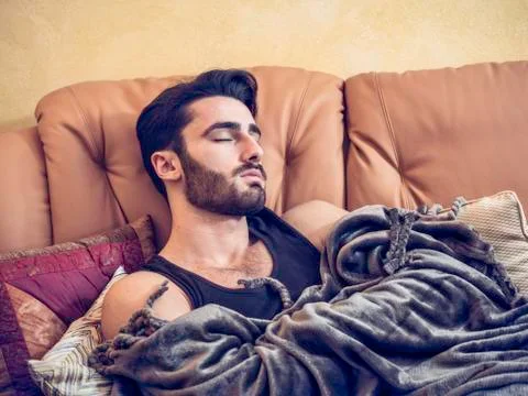 Young man lying alone on a couch, sleeping Stock Photos