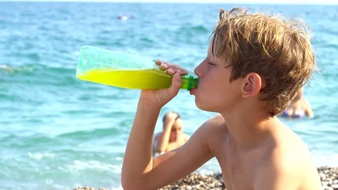 Young man lying by the beach and drinking exotic drink Stock Footage 79865812