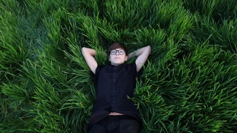 A young man lying in a beautiful field of green grass. Stock-Footage 274159859