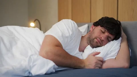 A young man is lying in bed and trying to fall asleep, but he can't fall asleep Stock Footage 233283003