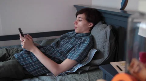 Young man lying in bed, cellphone, using phone, texting, relaxing, home Stock Footage 51677327