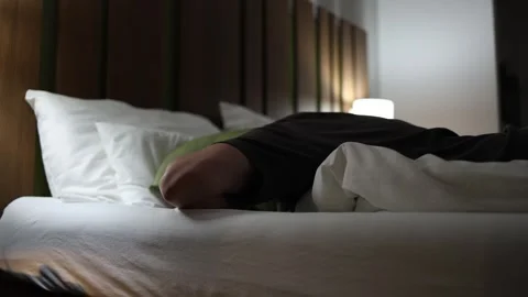Young man lying in bed covering head with pillow annoyed by loud neighbors unabl Видео 318778742
