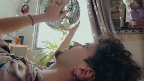 Young Man Lying on Bed with Disco Ball Stock Footage 235659422