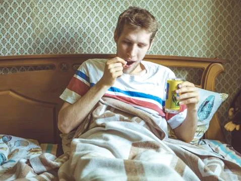 Young man lying in bed drinking tablets with glass of water Stock Photos