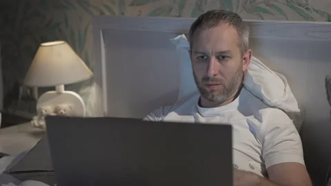 Young man lying in the bed with laptop before sleeping Stock Footage 160534058