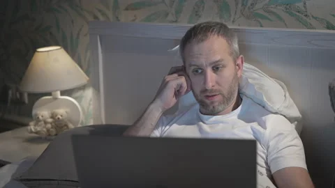 Young man lying in the bed with laptop before sleeping Stock Footage 161567826
