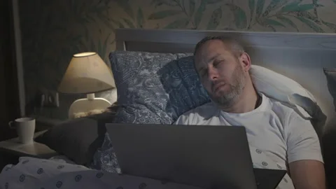 Young man lying in the bed with laptop and sleeping Stock-Footage 164872281