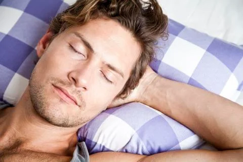 Young man lying in bed Stock Photos