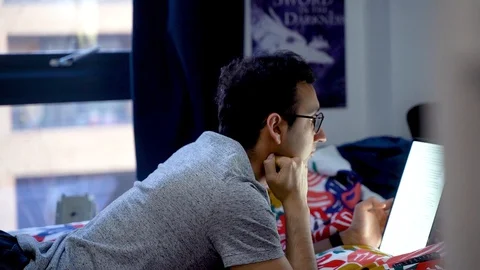 Young man lying in bed reading on iPad Pro, scrolling, reading, bedroom, home Stock-Footage 129153634