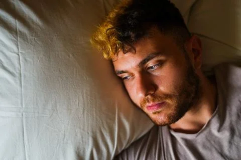 Young man lying in bed resting Stock Photos