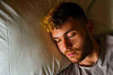 Young man lying in bed sleeping Stock Photos
