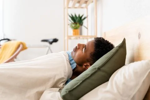 Young man lying in bed sleeping on sunday morning. Stock Photos