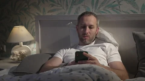 Young man lying in the bed with smartphone before sleeping. Stock Footage 160441822