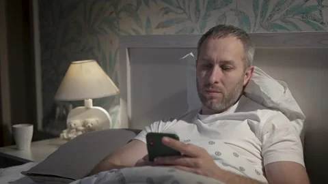 Young man lying in the bed with smartphone before sleeping. Stock Footage 161812551