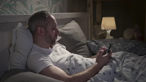 Young man lying in the bed with smartphone before sleeping. Stock Footage 161913528
