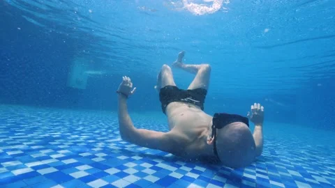 Young man lying on the bottom of the pool mastering to make bubble rings Stock Footage 149554884