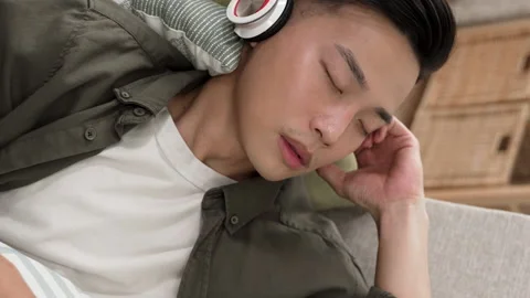 Young man lying on the couch with headset Stock Footage 227098159
