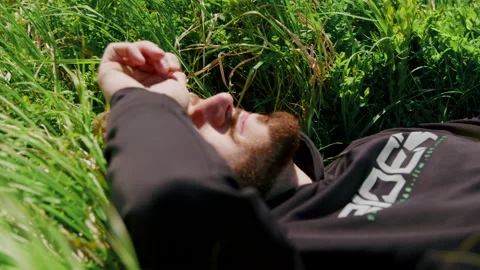Young man lying down in the grass alone in nature 4K. Stock Footage 234566194