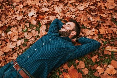 Young man lying down on the ground covered in autumn leaves Stock Photos