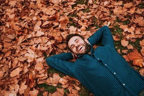Young man lying down on the ground covered in autumn leaves Stock Photos