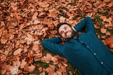 Young man lying down on the ground covered in autumn leaves Stock Photos
