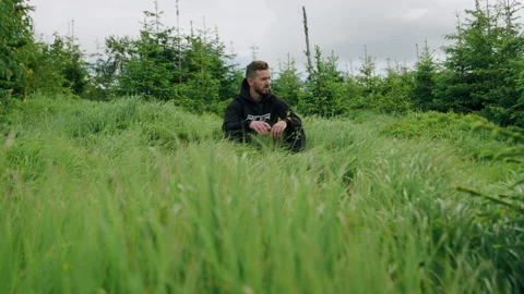 Young man lying down in the high grass in the forest, nature in the mountains. Stock Footage 234564030