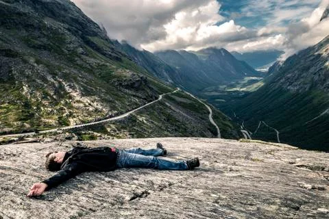 Young man is lying down on the stone, Trollstigen, Norway Stock-Fotos