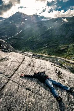 Young man is lying down on the stone, Trollstigen, Norway Stock Photos