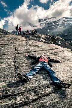 Young man is lying down on the stone, Trollstigen, Norway Stock-Fotos