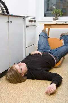 Young man lying on the ground after falling back in a chair Stock Photos