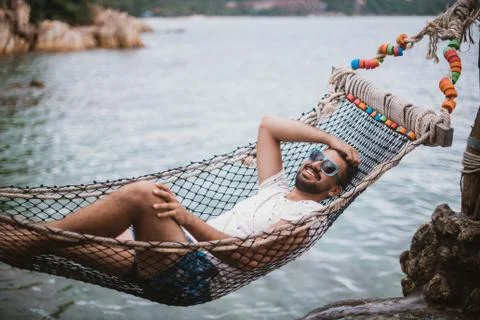 Young man lying in a hammock by the ocean. Stock Photos
