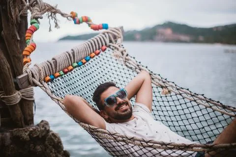 Young man lying in a hammock by the ocean. Stock Photos