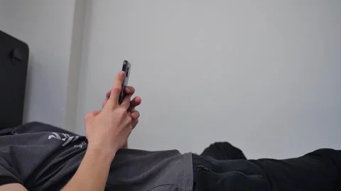 The young man lying on his bed is busy on the phone Stock Footage 270314631
