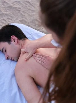 A young man lying on a massage table receiving a chiromassage treatment on the Stock Photos