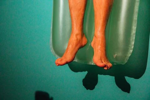 Young man lying on a pool float on a warm summer day Stock Photos