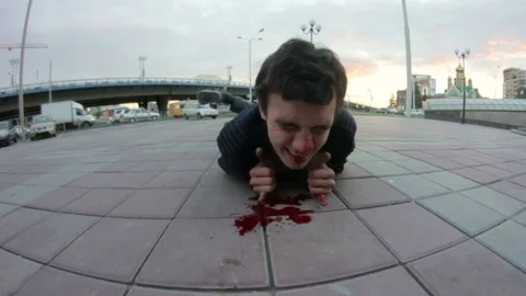 Young man lying on the sidewalk and bleeding Stock Footage 69789279