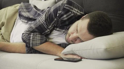 Young man lying on the sofa with face down, tired after working day. Slow motion Stock Photos