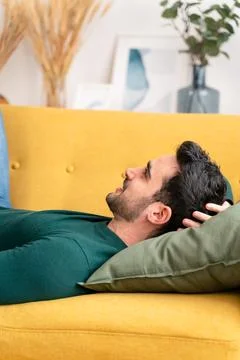 Young man lying on sofa Stock Photos