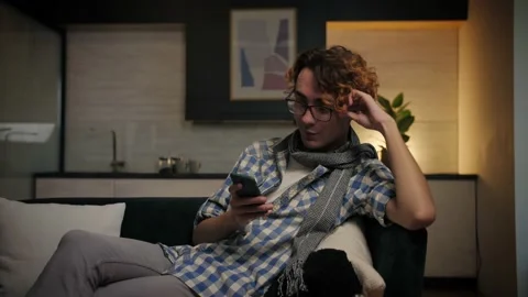 Young man lying at sofa using phone browsing internet.Relaxed guy lazily Stock Footage 221618699