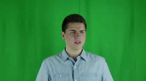 Young man is mad and flips off camera in front of a greenscreen Vidéo 59083268