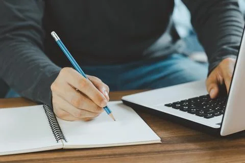 Young man make notes sit at work desk while study online watching webinar pod Stock Photos